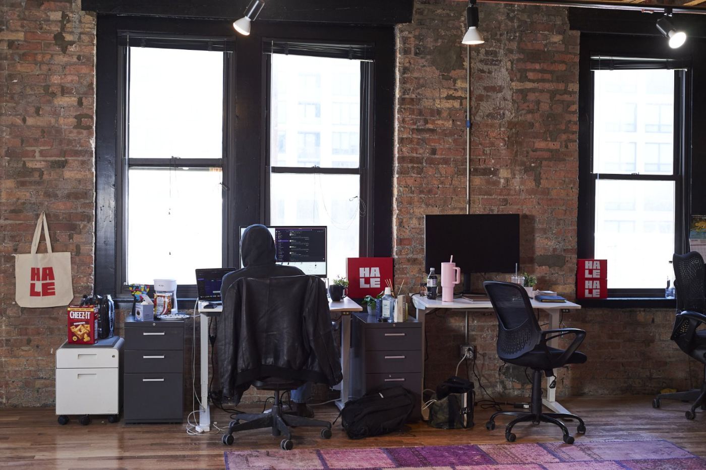 Desks along the brick wall and tall windows of the Superior Studios office