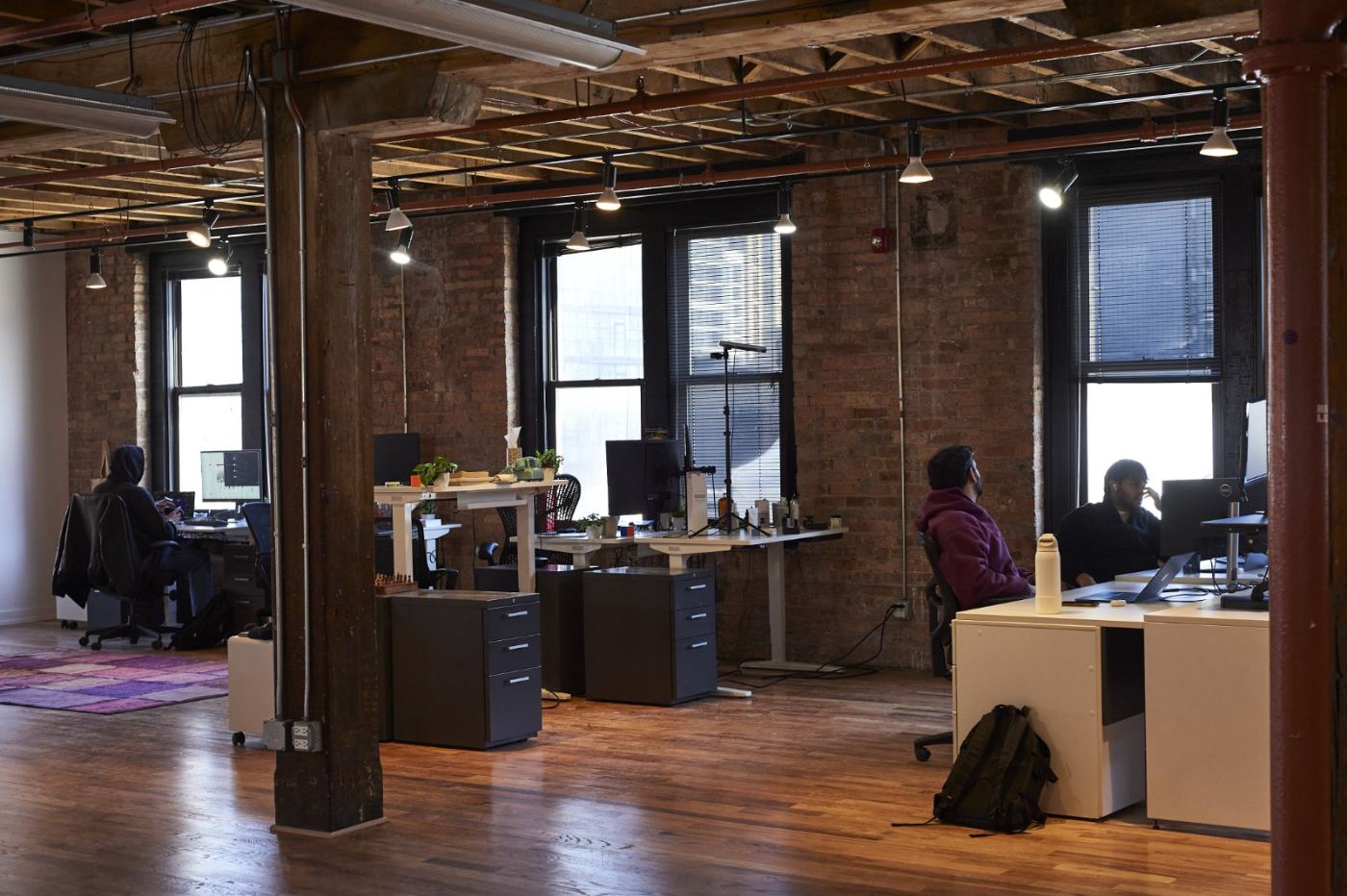 The open studio floor, with exposed beams, brick walls, and founders at their desks